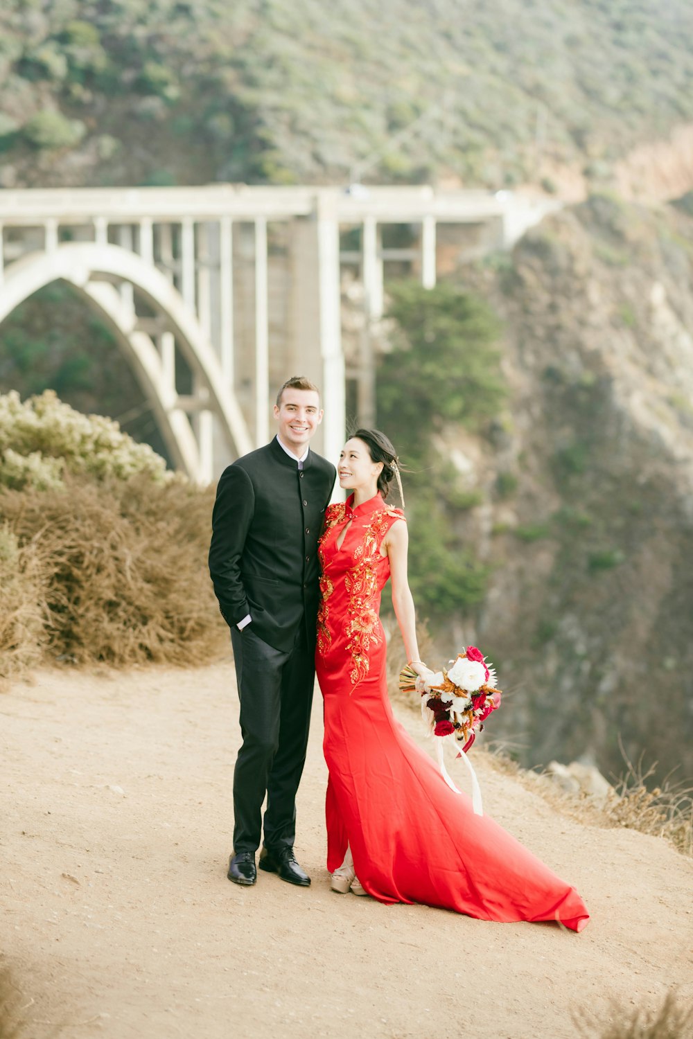 man in black suit and woman in red dress holding bouquet of flowers