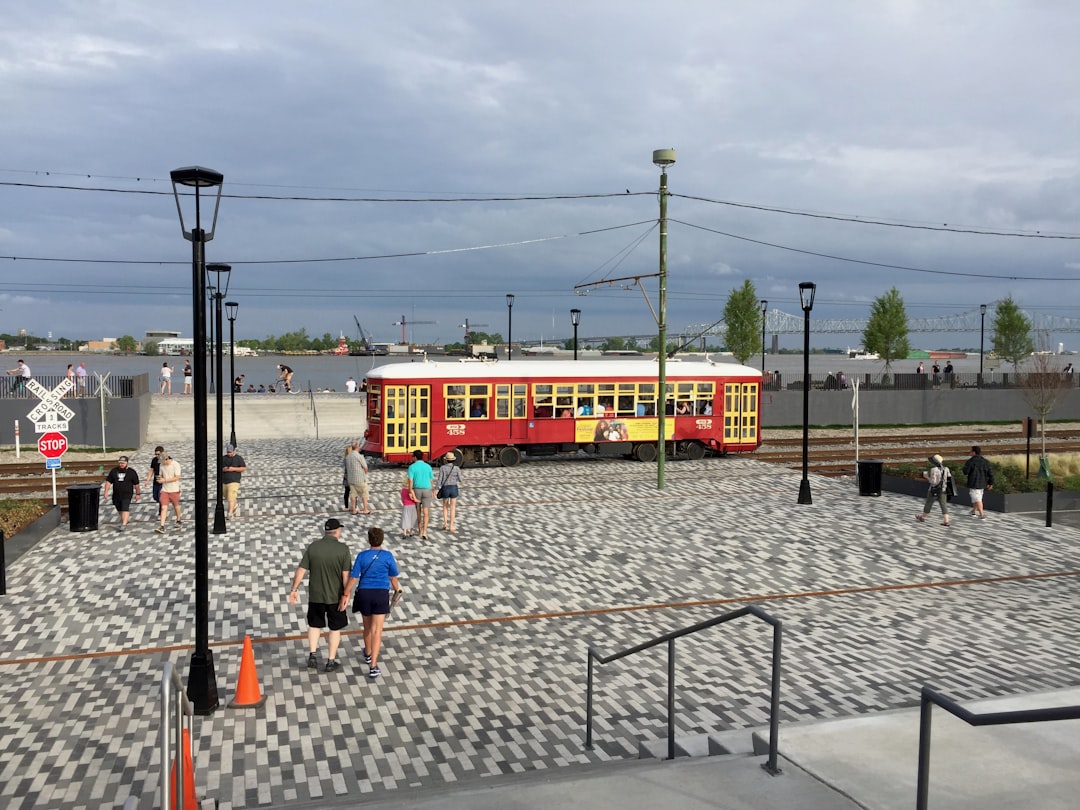 people walking on sidewalk near red and yellow train during daytime