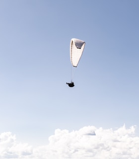 person in parachute under blue sky during daytime