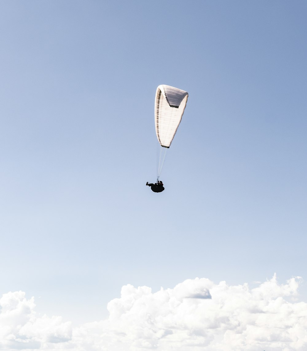 낮 동안 푸른 하늘 아래 낙하산을 탄 사람