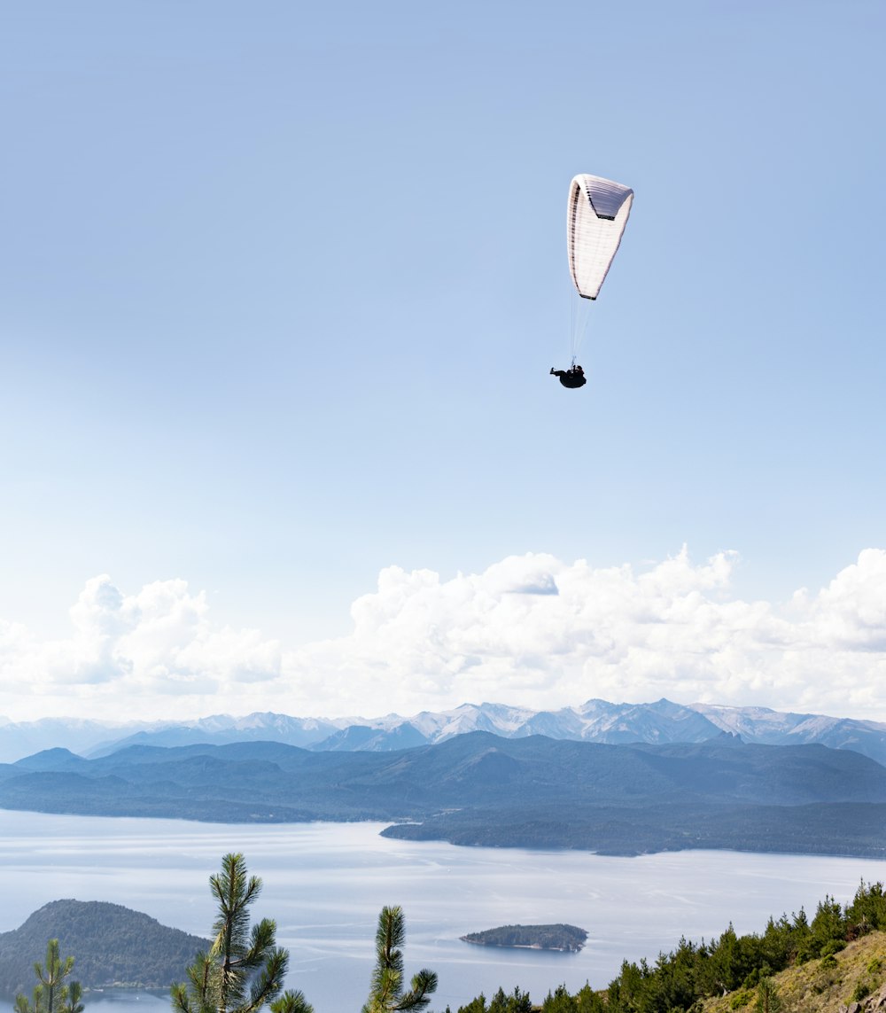 person in parachute over green trees and mountains during daytime