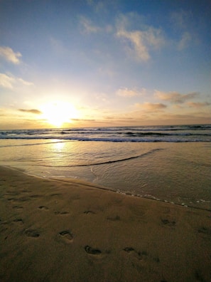 Sunset view of Kovalam beach with gentle waves and golden sky.
