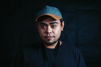 Model wearing a pastel celeste embroidered cap under soft urban lighting.