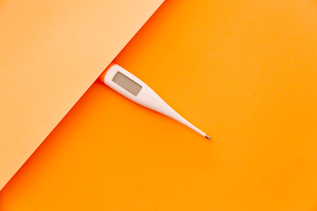 Termometer digital putih di atas kain kuning