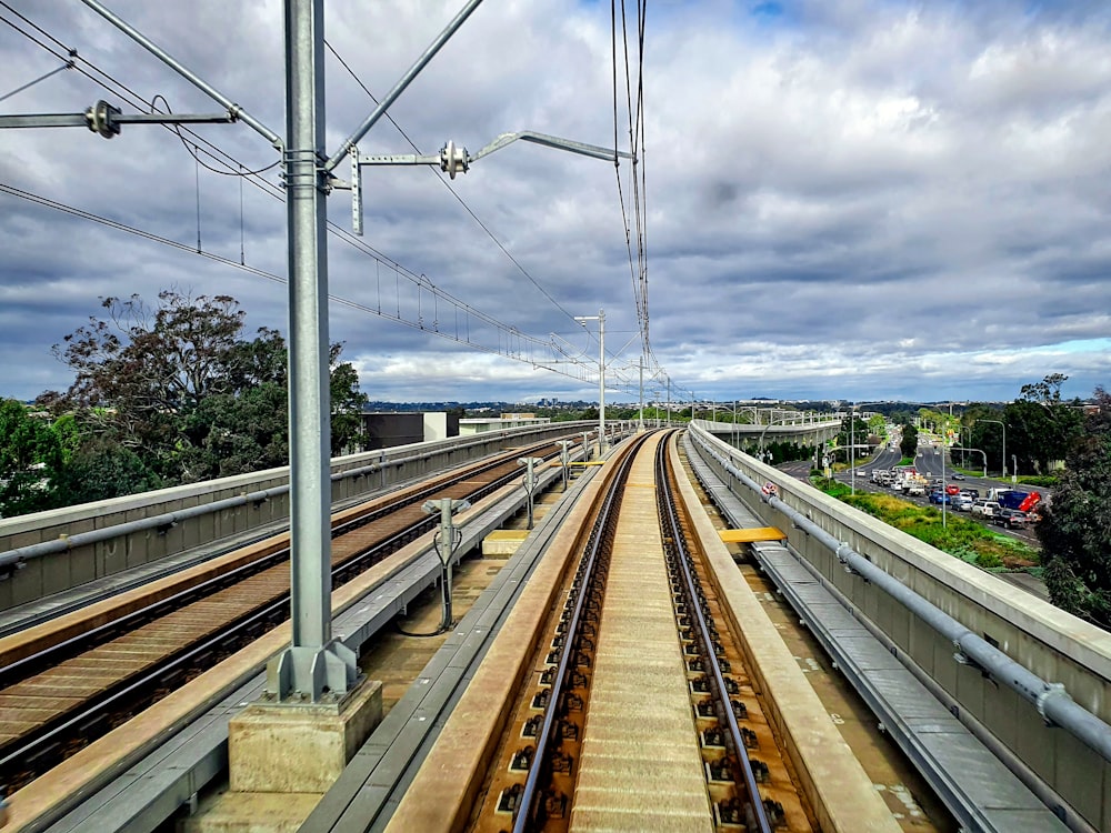 rotaia marrone e grigia del treno sotto il cielo nuvoloso grigio durante il giorno