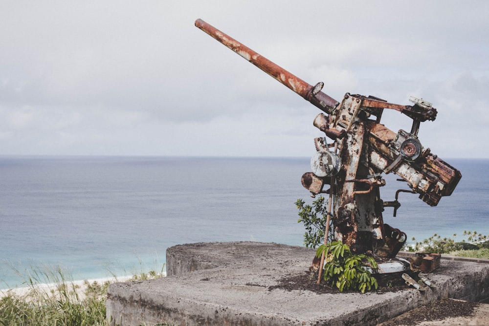 brown metal machine on gray concrete wall near sea during daytime