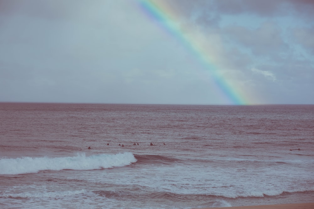 ocean waves under rainbow during daytime