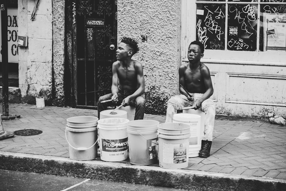 grayscale photo of topless man and woman standing beside concrete wall