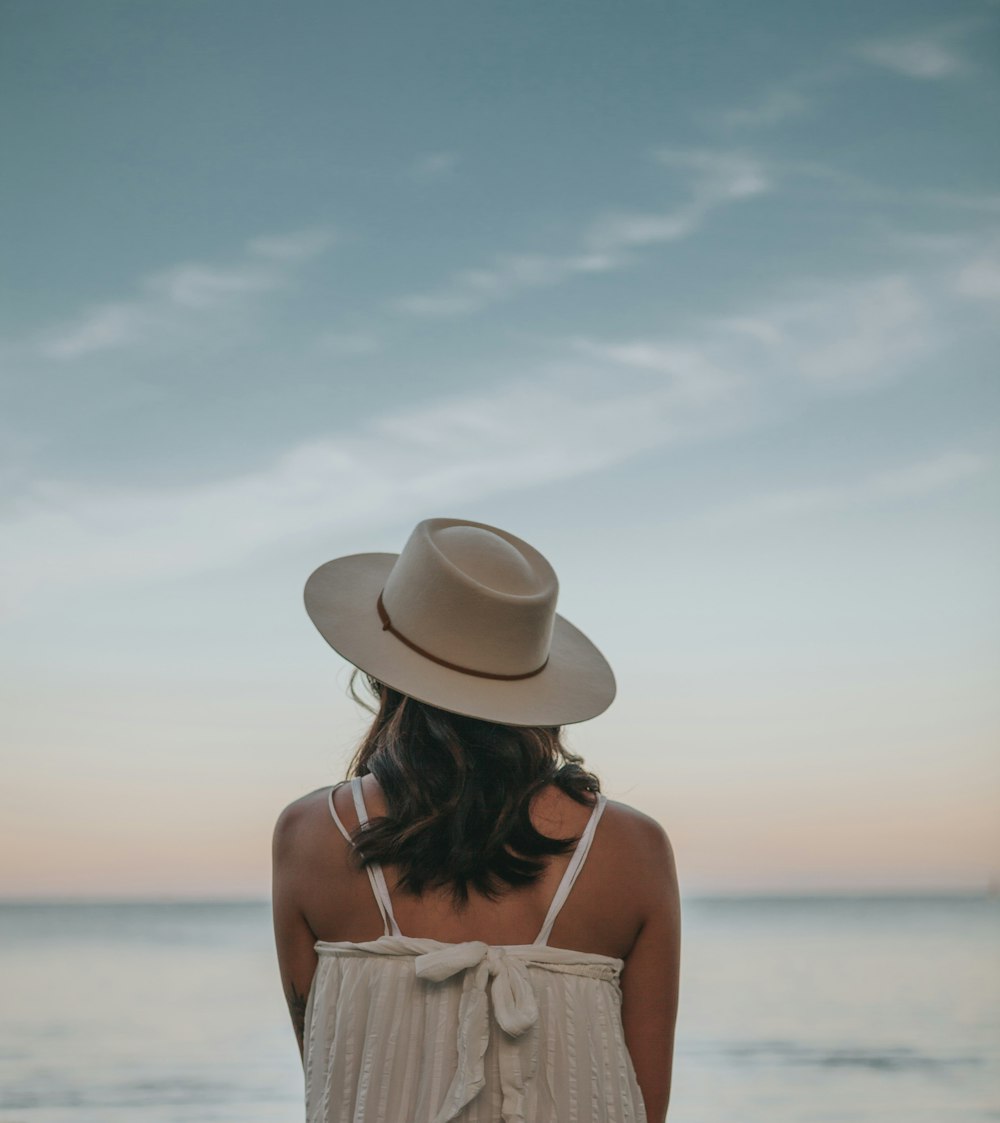 woman in white fedora hat standing on beach during daytime