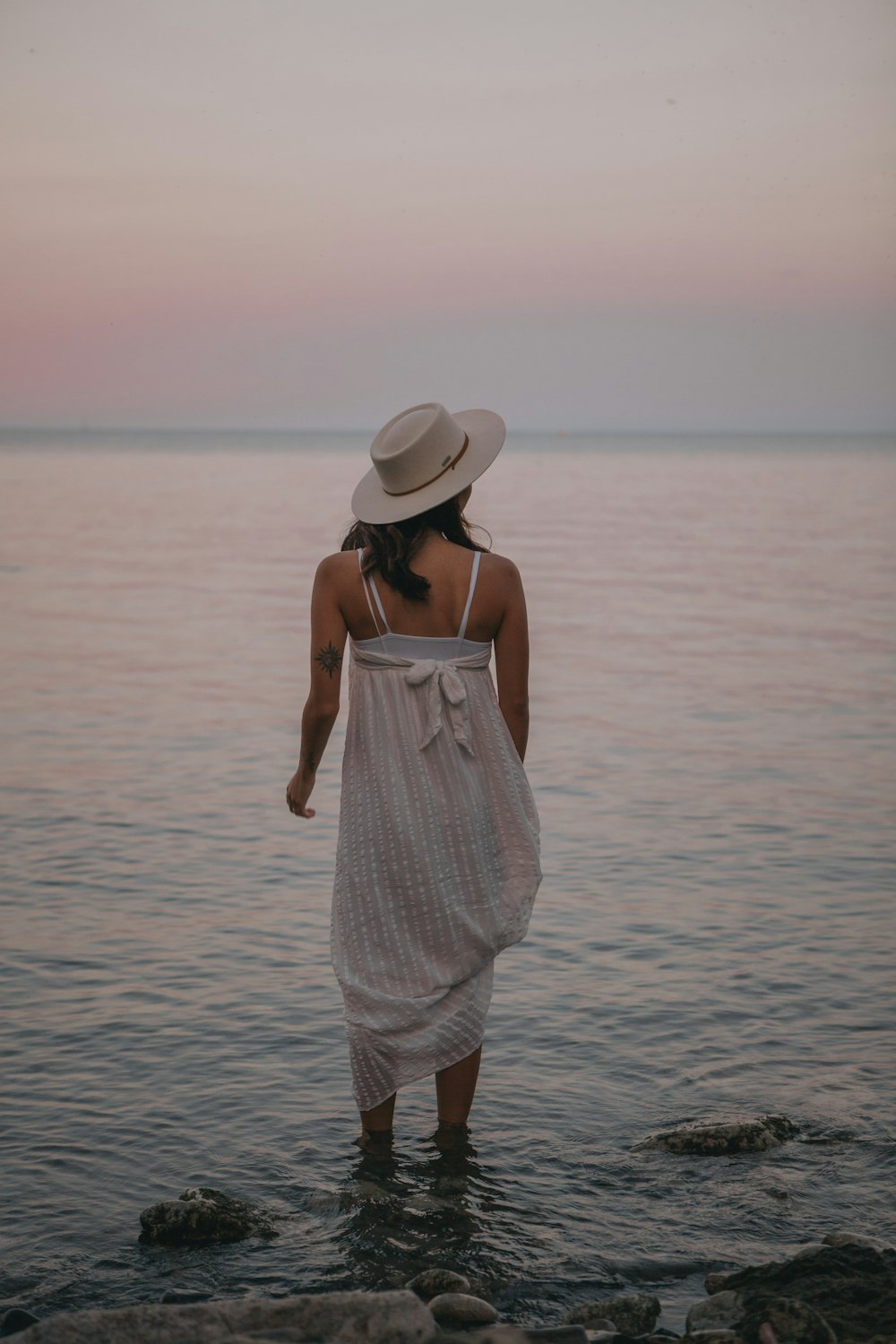 woman in white spaghetti strap dress standing on sea shore during daytime