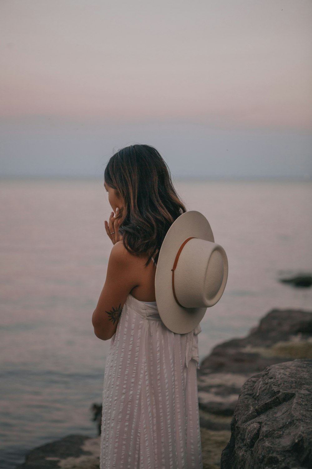 woman in white dress standing on rock near sea during daytime