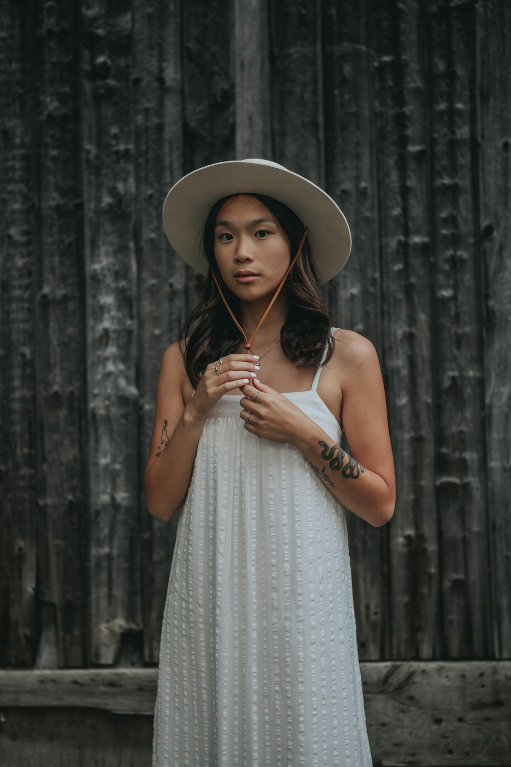 woman in white spaghetti strap dress wearing brown sun hat