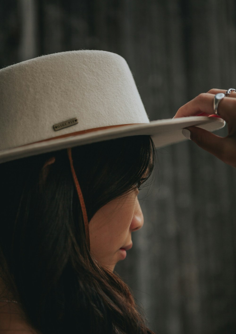 woman in white hat holding smartphone