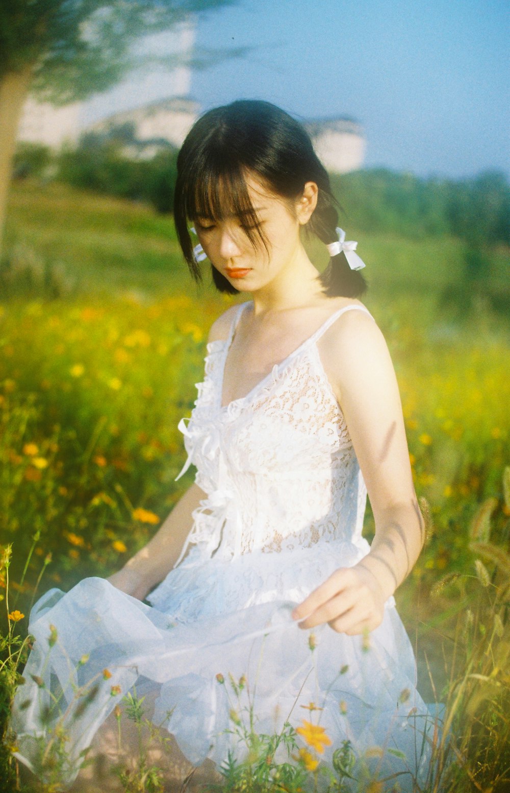 woman in white floral dress sitting on green grass field during daytime