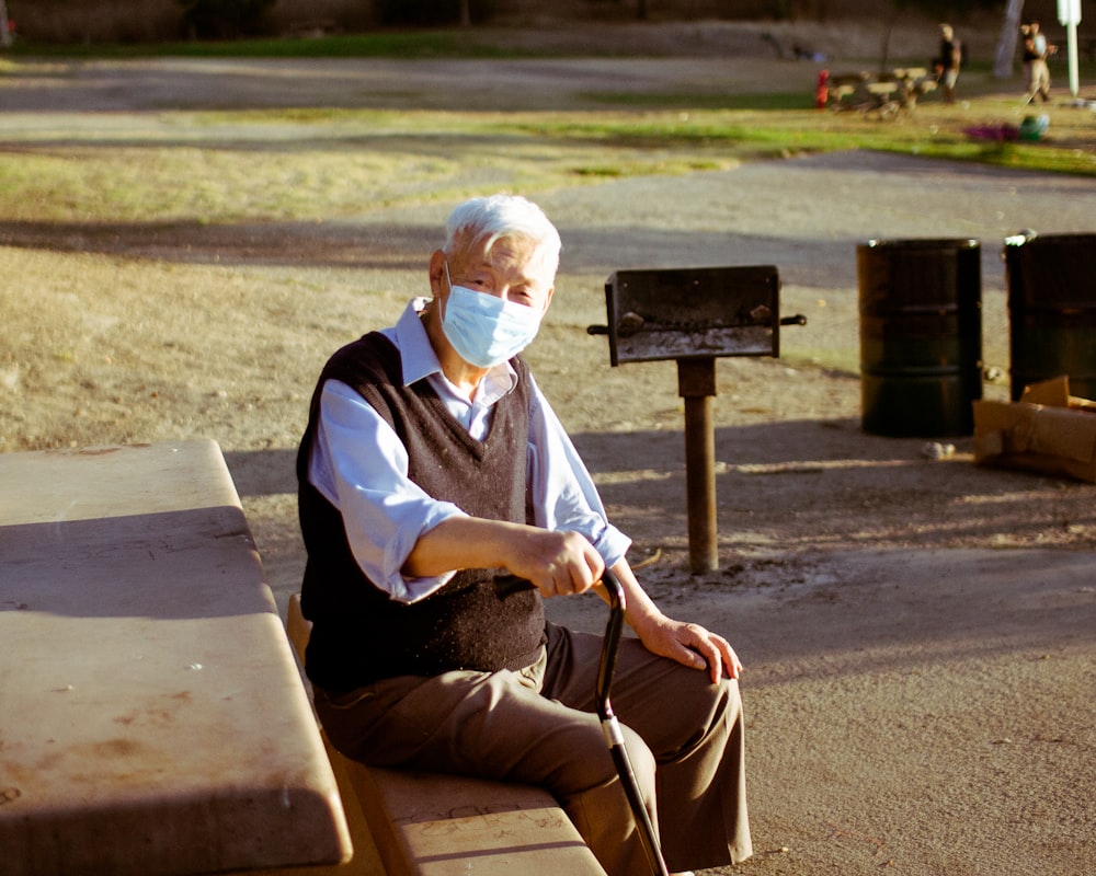 man in white and blue long sleeve shirt sitting on brown wooden bench during daytime