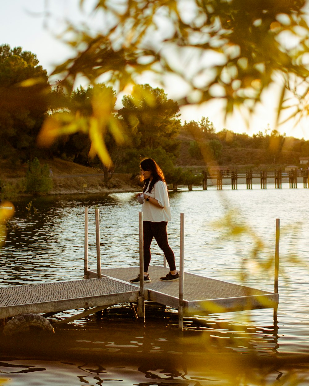 woman in white long sleeve shirt and black pants standing on dock during daytime