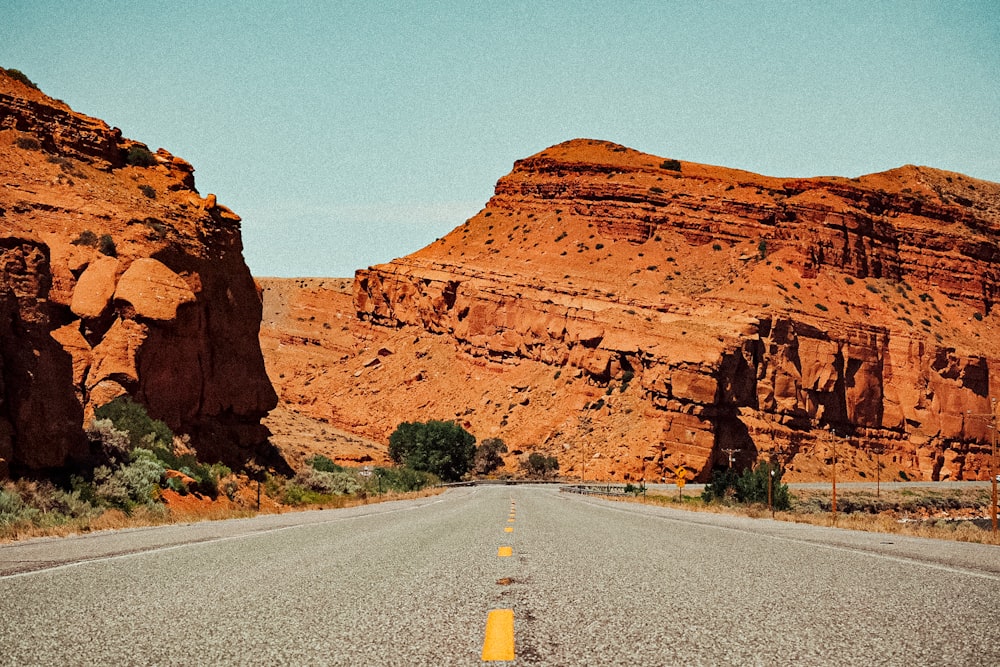 gray asphalt road near brown rock formation during daytime