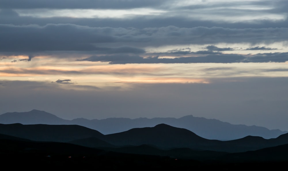 silhouette of mountains under cloudy sky during daytime