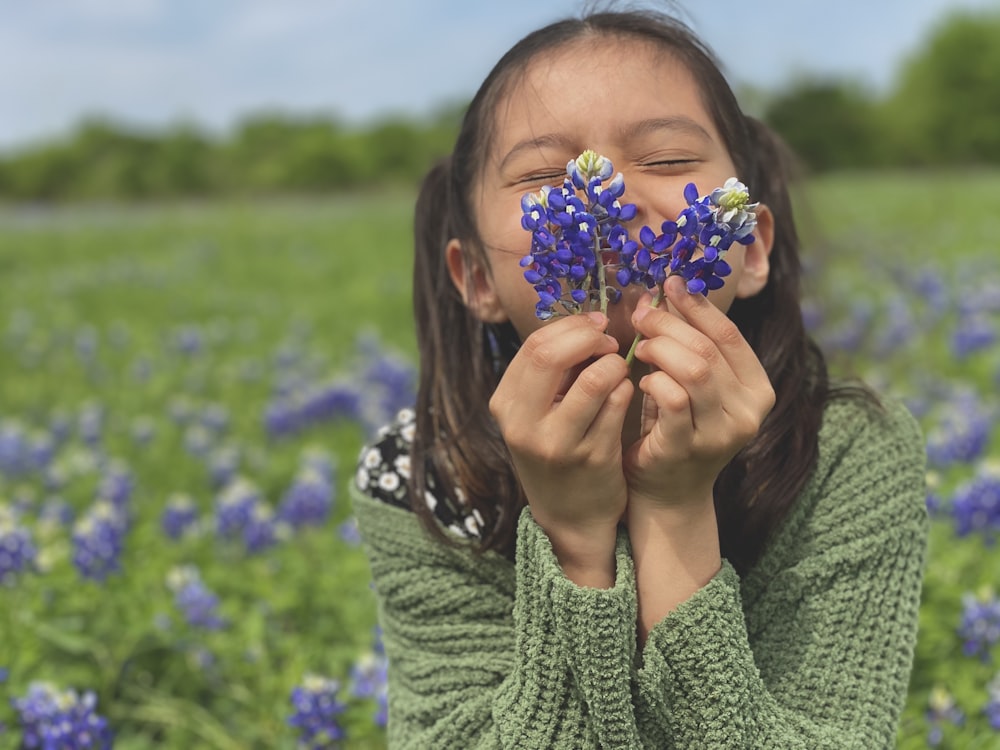 mulher no suéter de malha verde que segura a flor azul