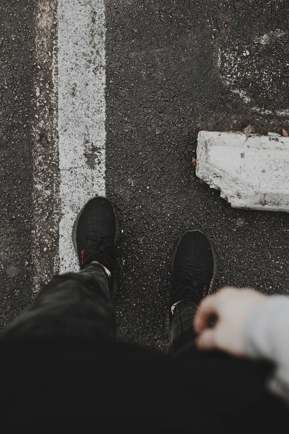 person in black pants and black shoes standing on gray concrete pavement