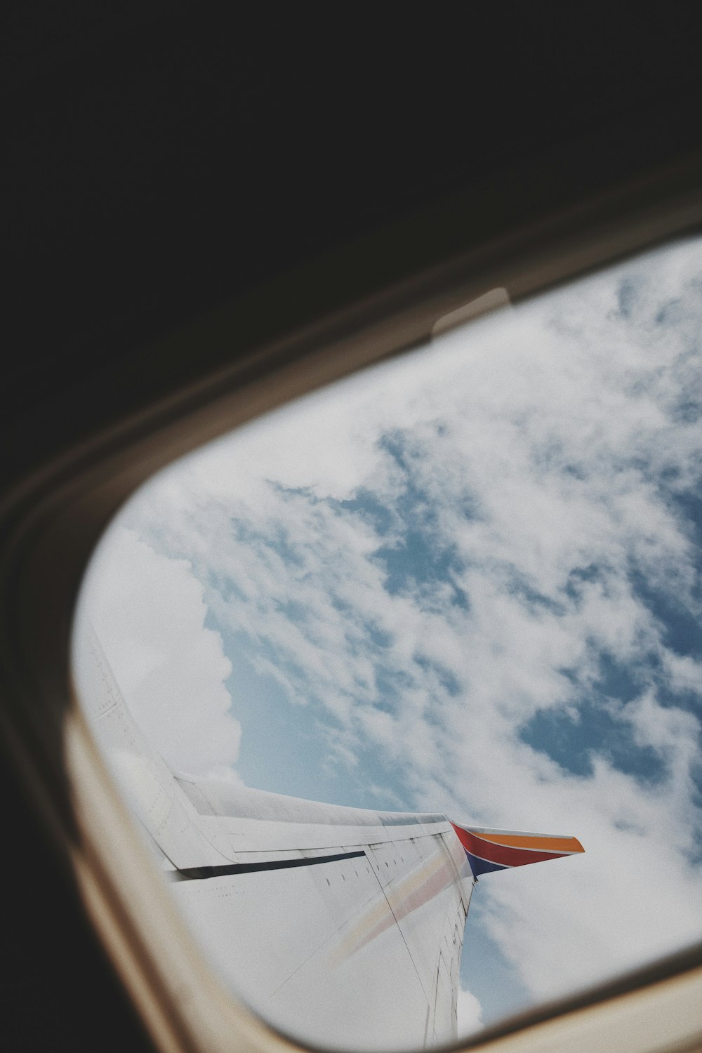 white and red airplane wing under white clouds and blue sky during daytime