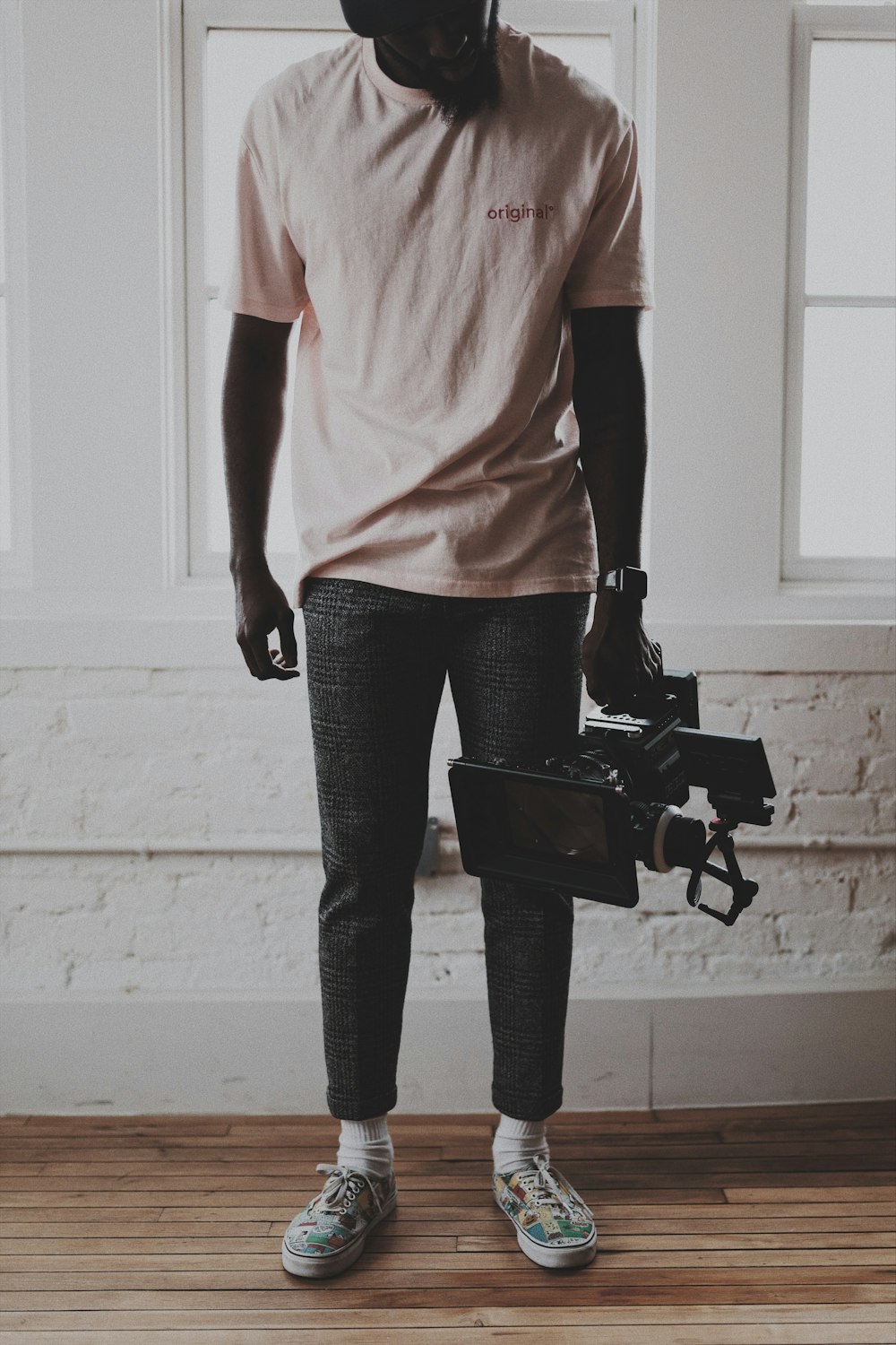 woman in pink shirt and black pants standing beside white wall