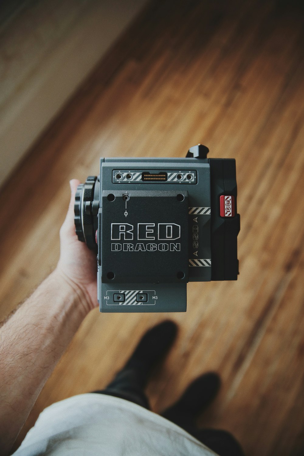 a person holding a camera on a wooden floor