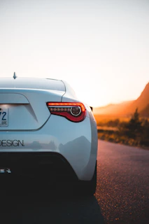A sleek white Swift parked beside a scenic Indian highway at sunset.