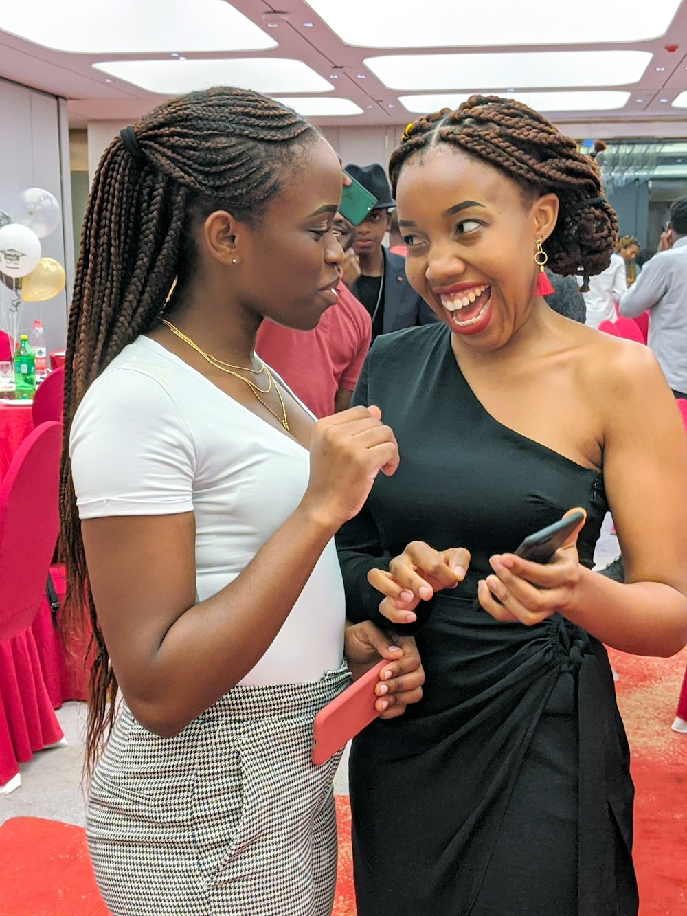 woman in white tank top smiling beside woman in black and white stripe dress