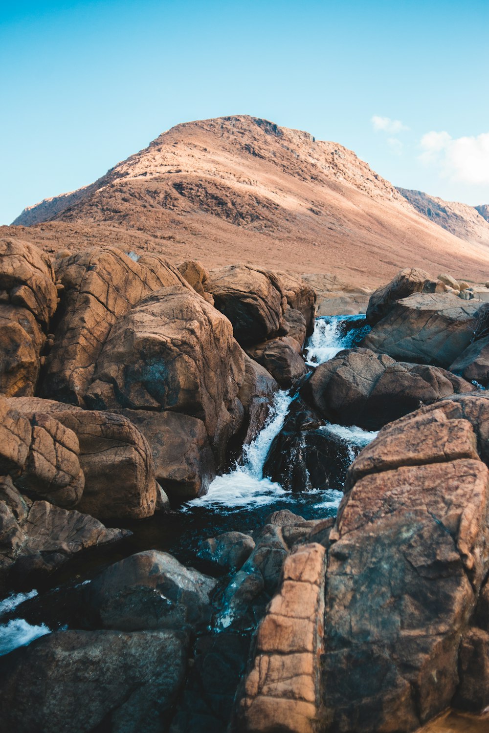 brown rocky mountain near body of water during daytime