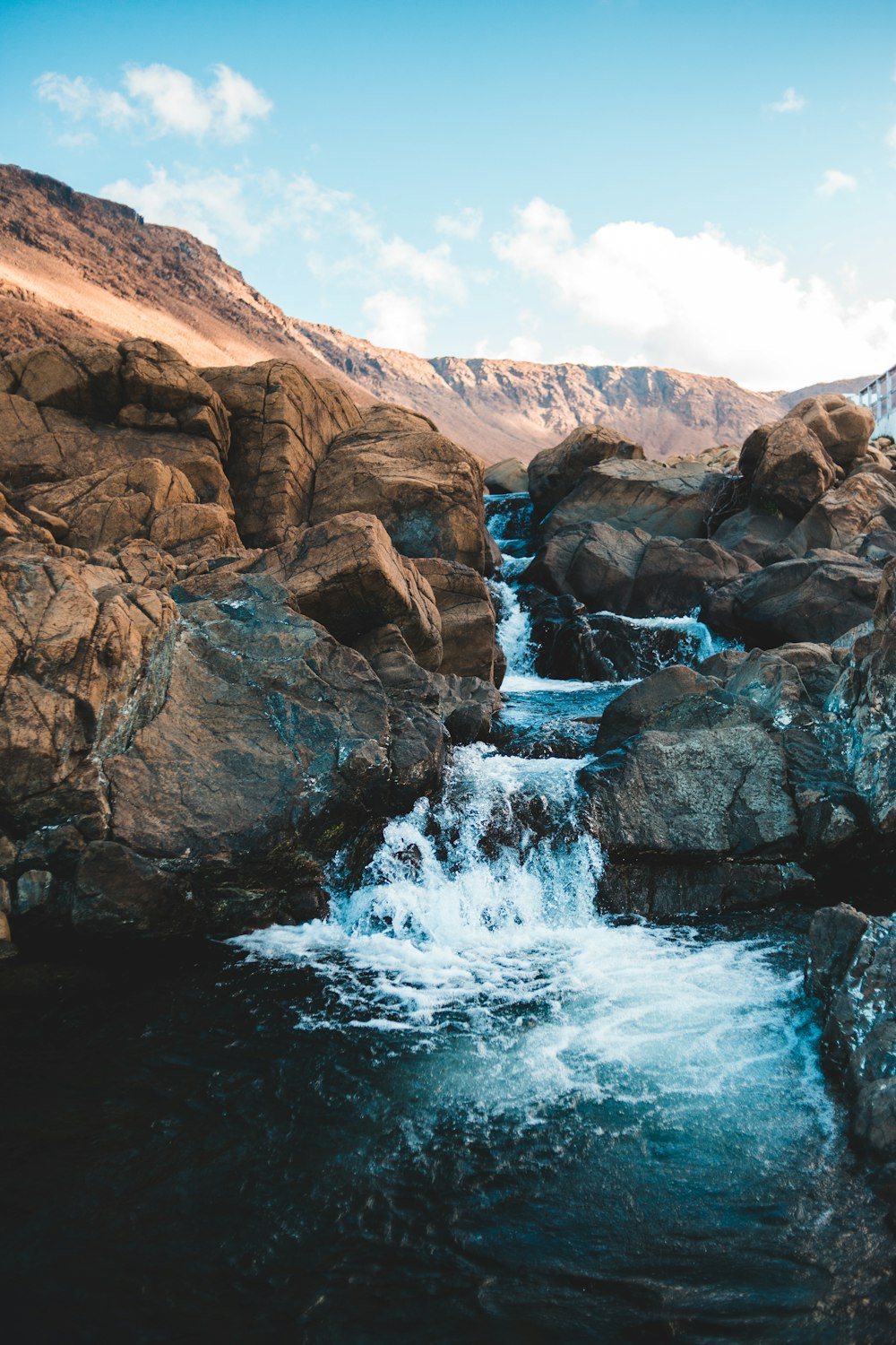 water falls on brown rocky mountain during daytime