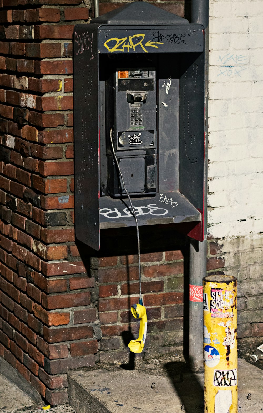 black telephone mounted on brown brick wall