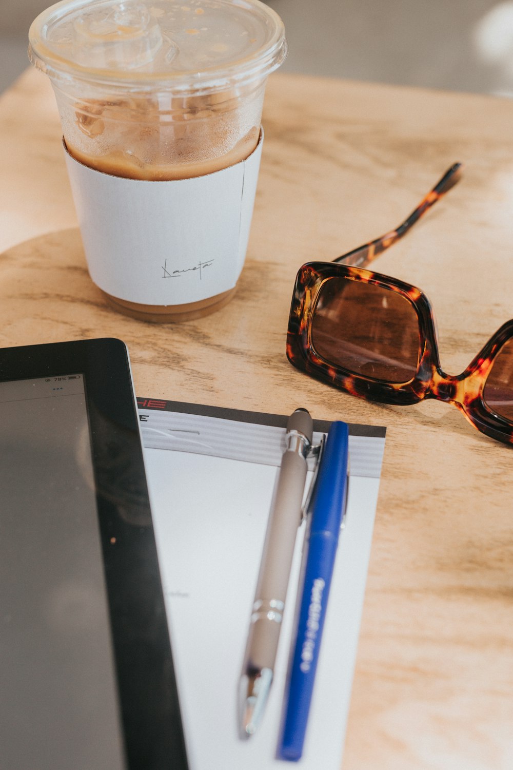 brown framed sunglasses beside white ceramic mug