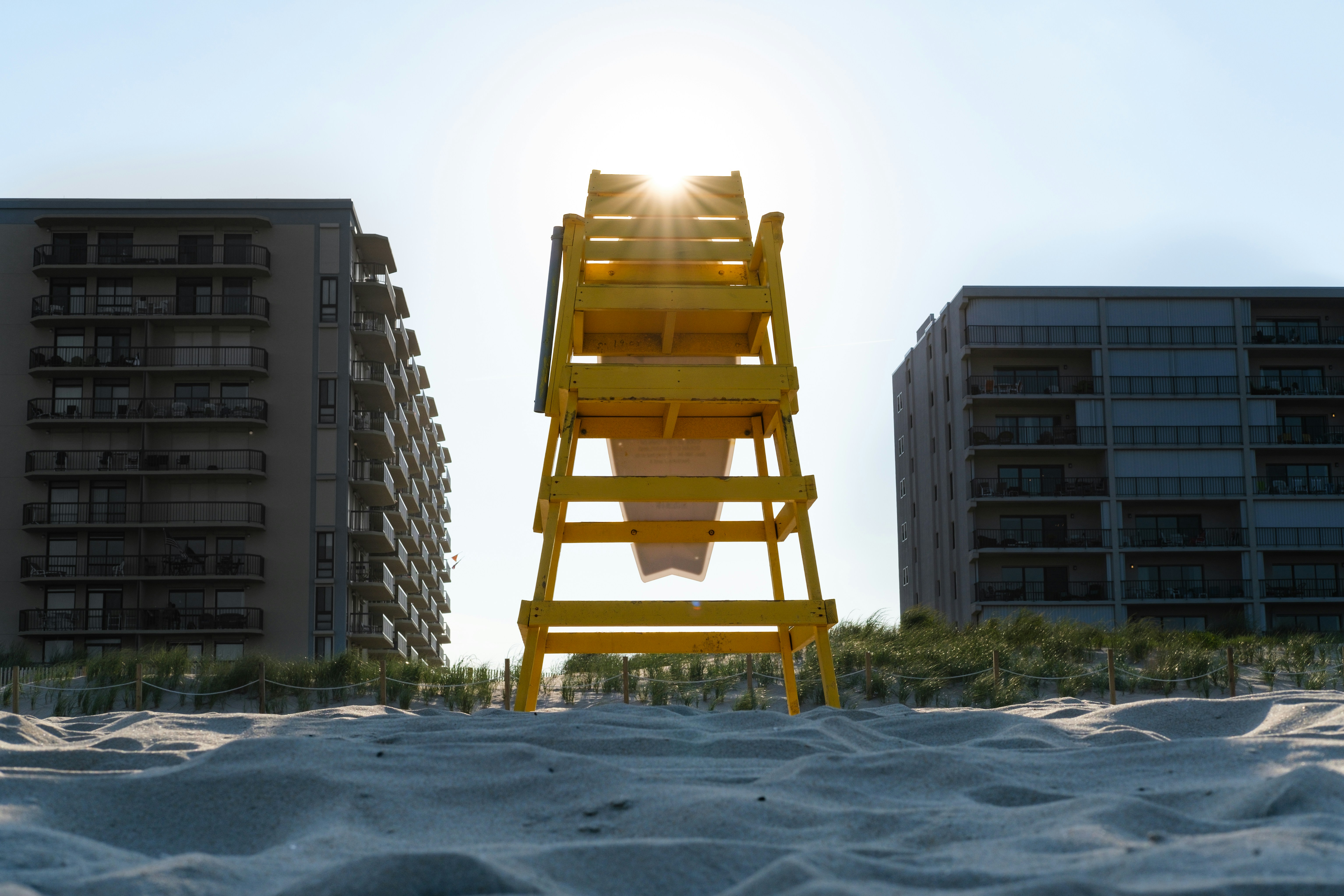 brown wooden chair on white sand near high rise building during daytime