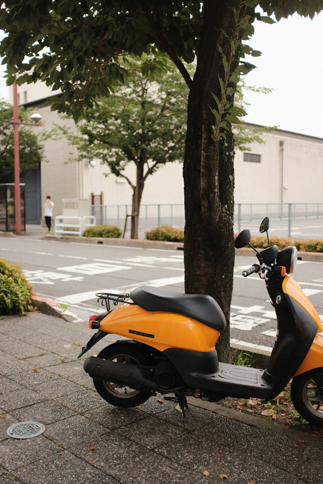 orange and black motor scooter parked on sidewalk during daytime