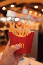 A friendly local restaurant owner smiling while holding a basket of golden crispy fries.