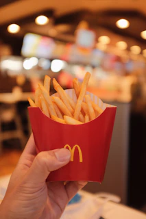 A happy customer smiling while holding a golden, crispy french fries container branded with savoré logo.