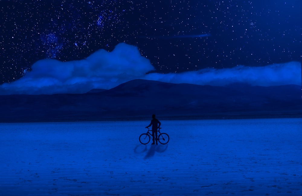 silhouette of man riding bicycle on snow covered ground during night time