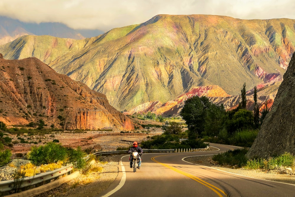 man riding bicycle on road near mountain during daytime