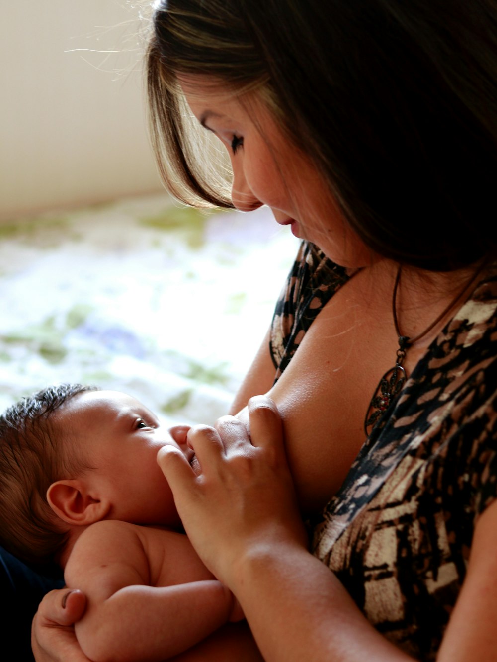 woman in black and white floral tank top carrying baby