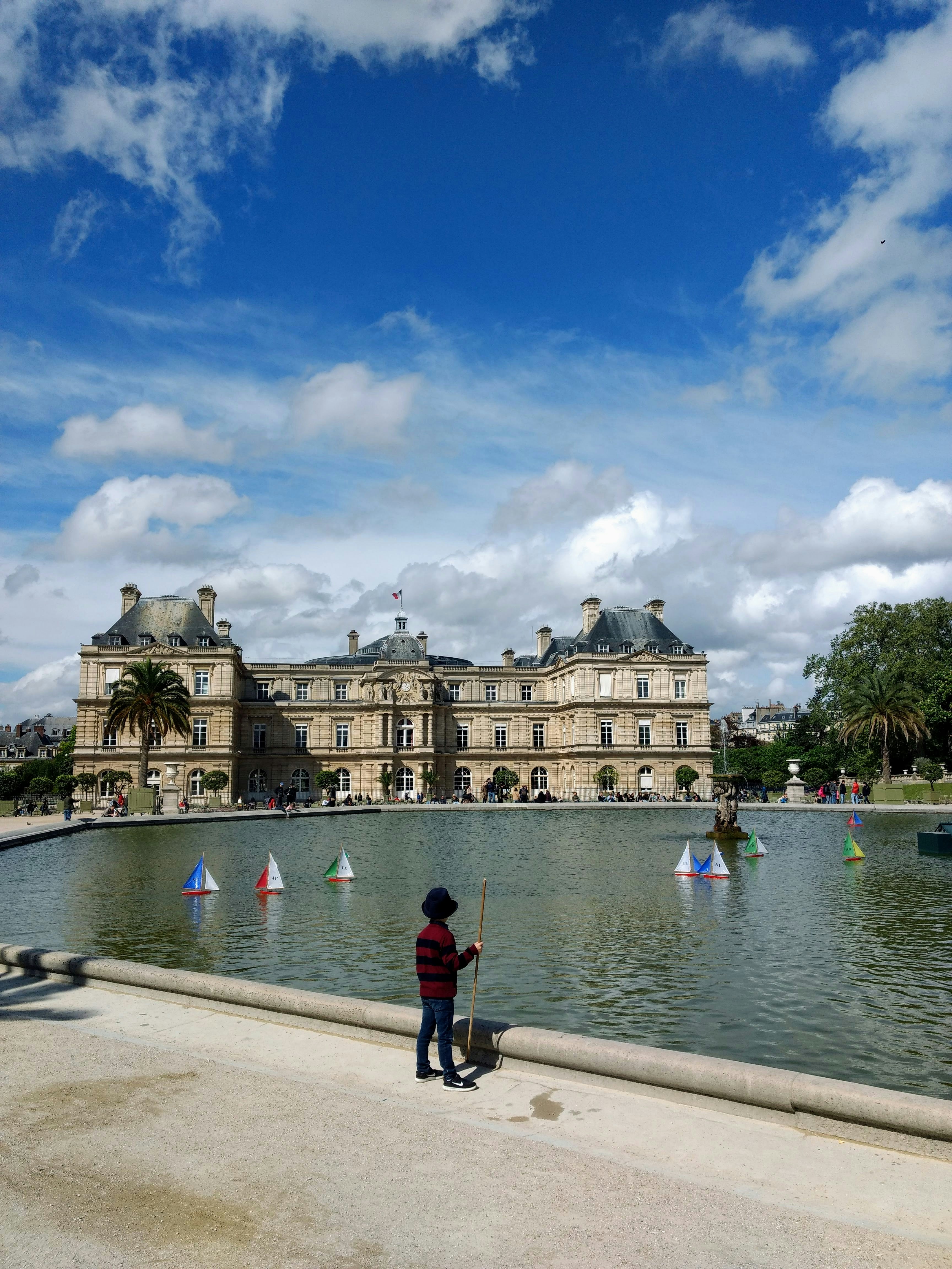 les personnes qui marchent sur le trottoir près d’un plan d’eau et d’un bâtiment pendant la journée ;