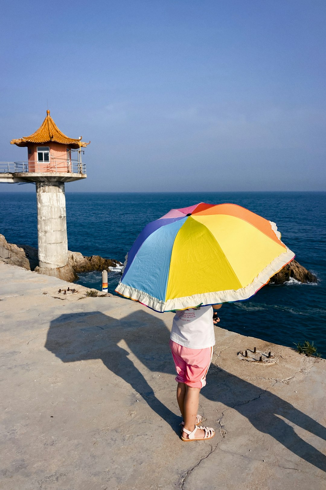 woman in white dress holding umbrella standing on beach during daytime