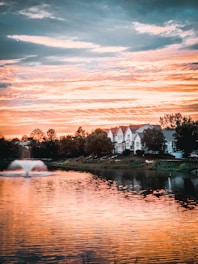 green grass field near body of water during sunset