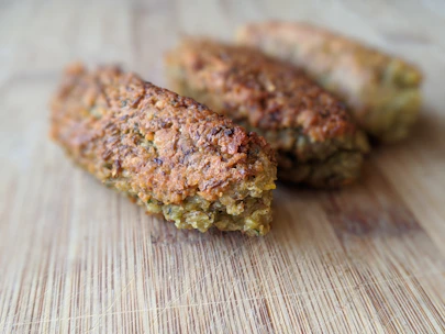 Golden, crispy broast pieces stacked on a rustic wooden platter with fresh herbs.
