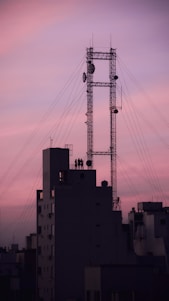 A team of engineers installing 5G network equipment on a city rooftop at sunset.