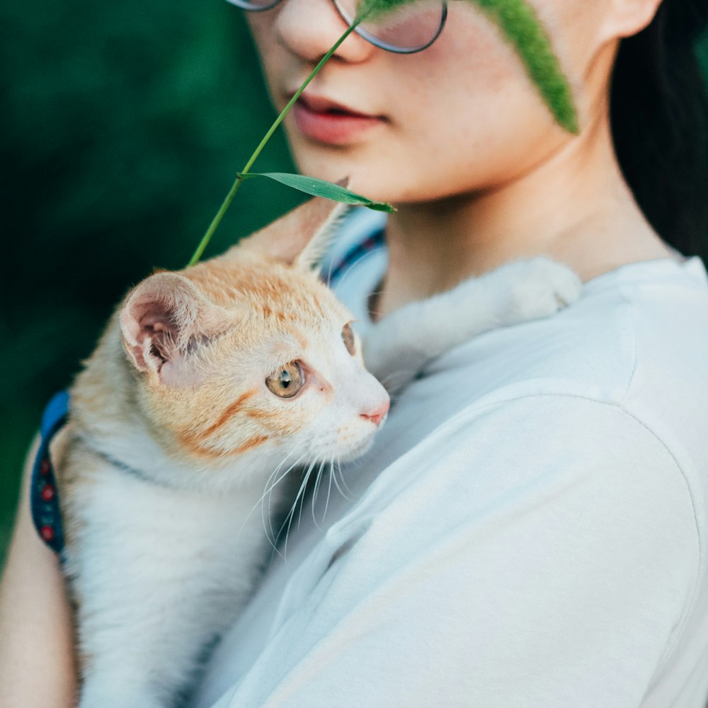 woman in white shirt holding white and orange cat