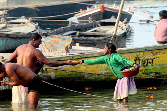 man in black shorts holding red and green boat paddle in Kashi India