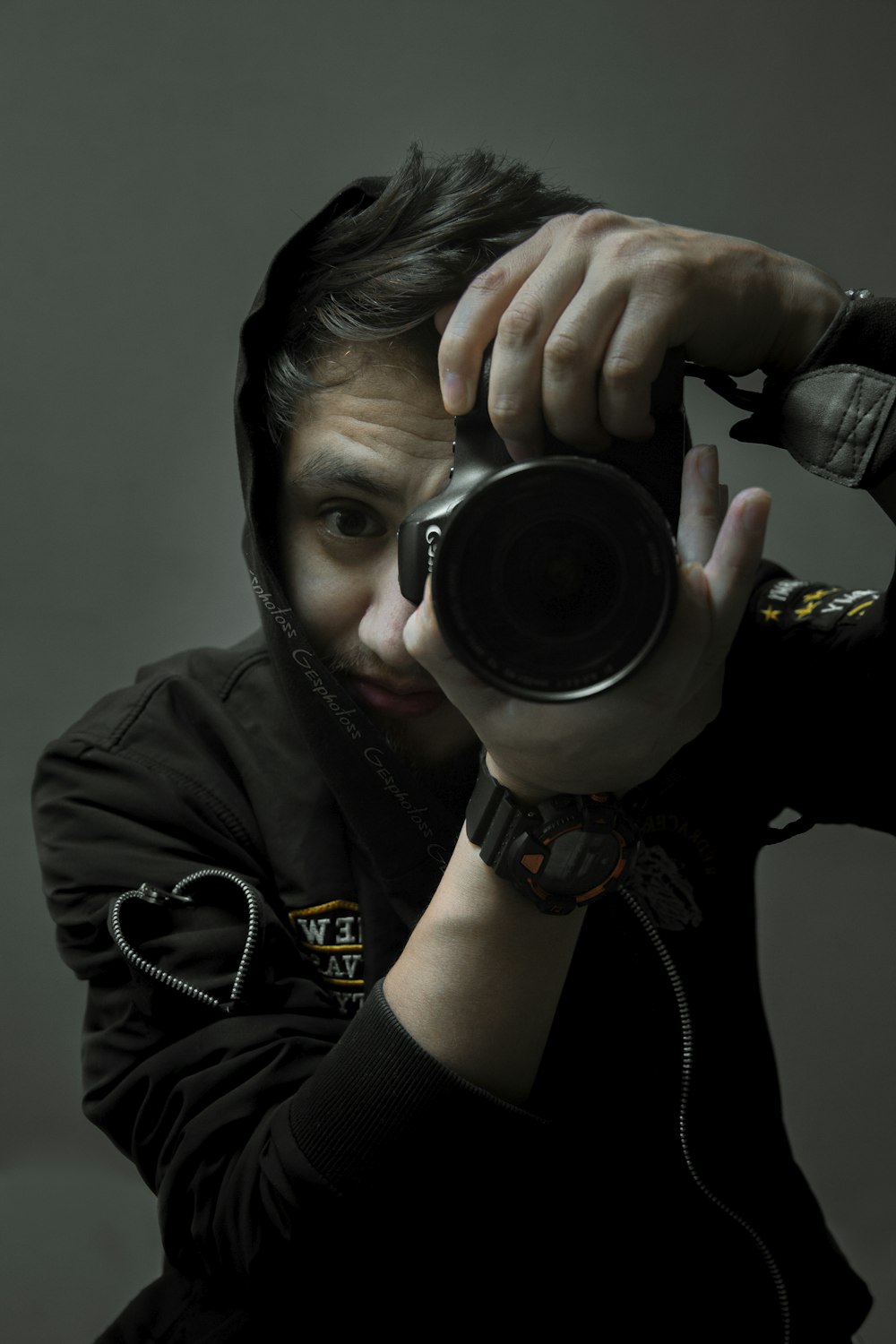 man in black leather jacket holding black dslr camera