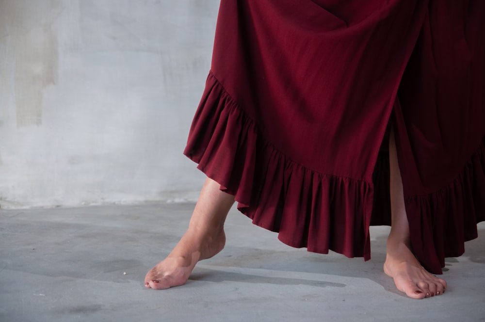 femme en robe rouge debout sur un sol en béton gris