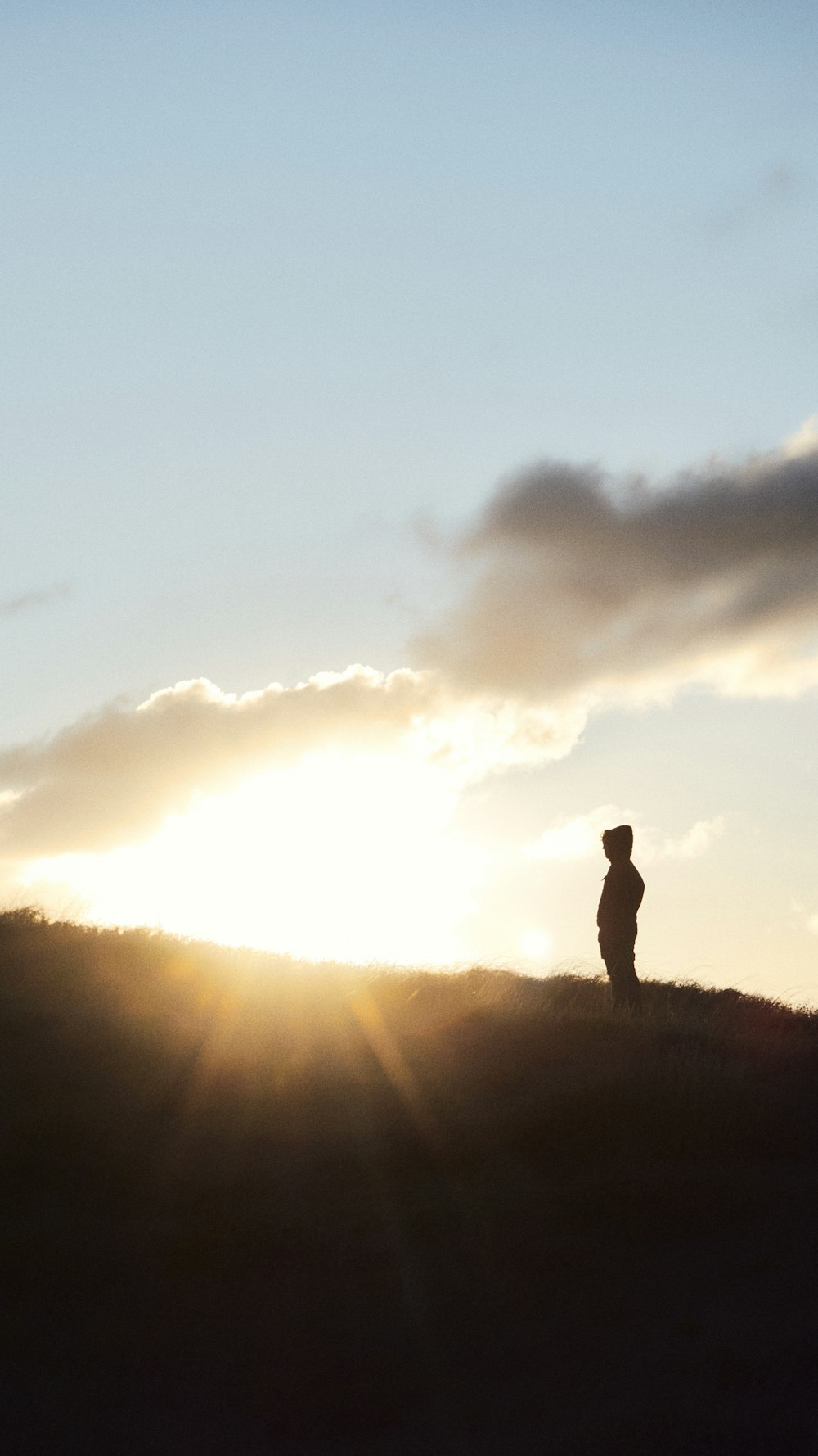 silhouette of man standing on hill during daytime
